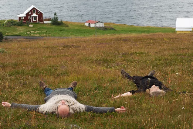 Two people are lying on a meadow with a slope. Photo.